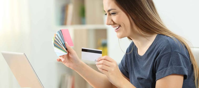 Happy shopper buying online with multiple credit cards and a laptop at home