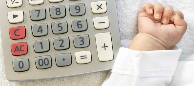Baby hand and a calculator. Image of childcare costs