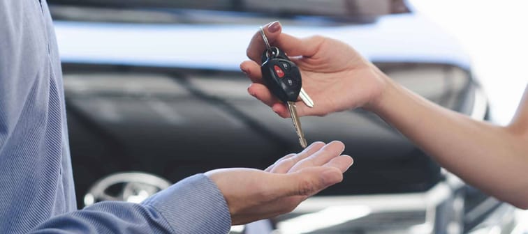 Concept car rental service. Close up view hands of agent giving car key to client that rent a vehicle  in rental office.