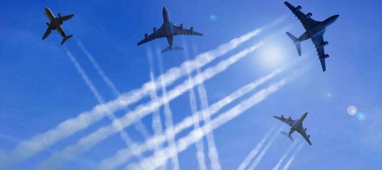 Airplanes fly against a blue sky, leaving contrails