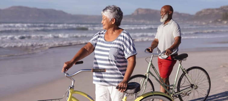 Senior african american couple with bicycles standing on the beach. travel vacation retirement lifestyle concept