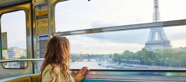 Beautiful young woman travelling in a train of Parisian underground and looking through the window at the Eiffel tower