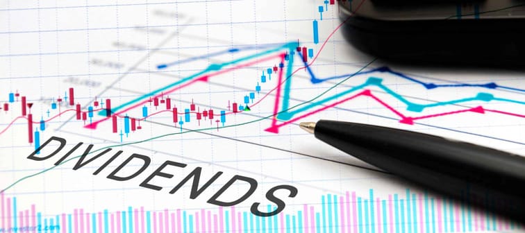 DIVIDENDS text on documents with graphs, charts, calculator, pen, financial concept background.