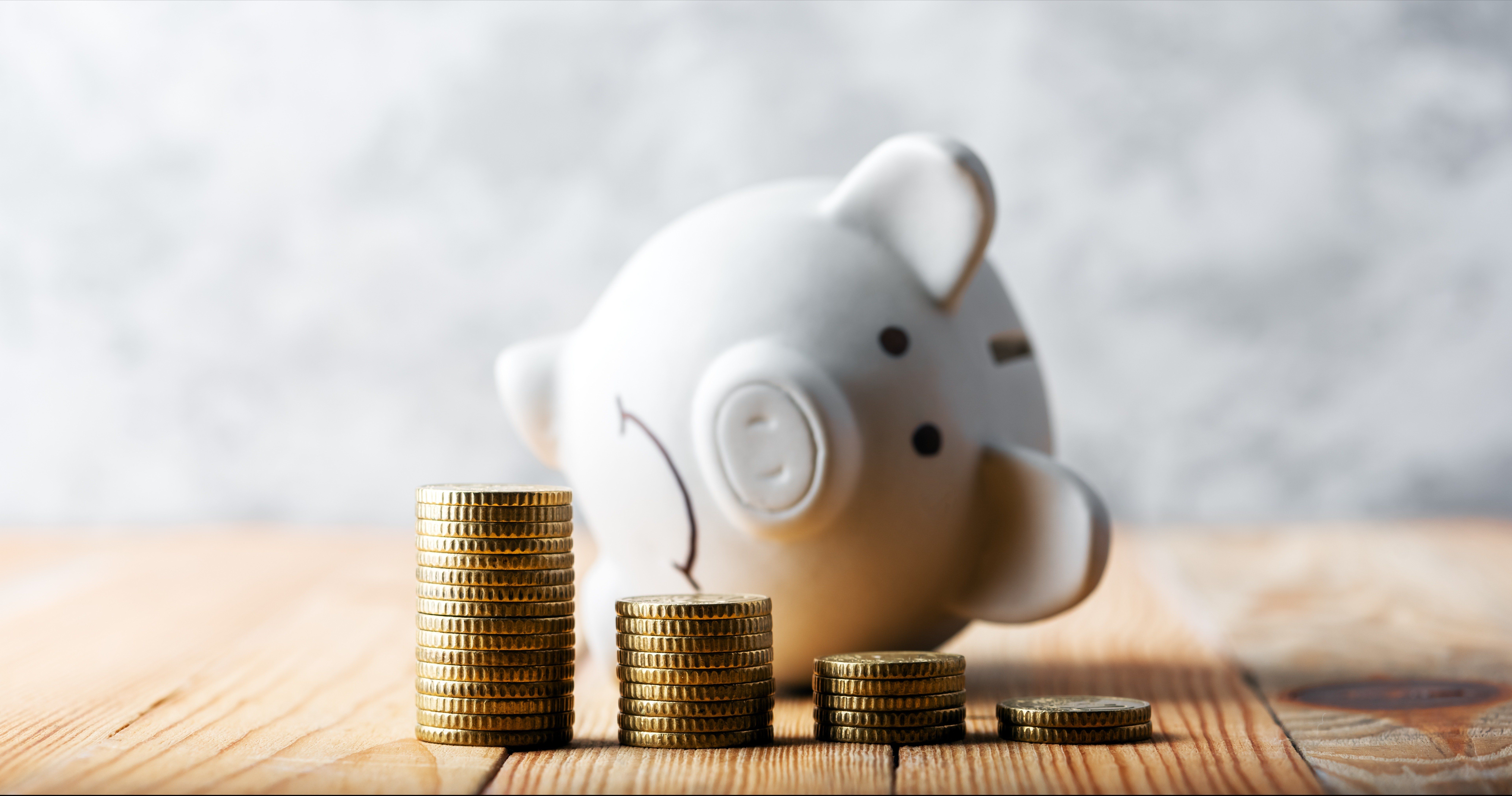 A sad piggy bank behind a stack of coins