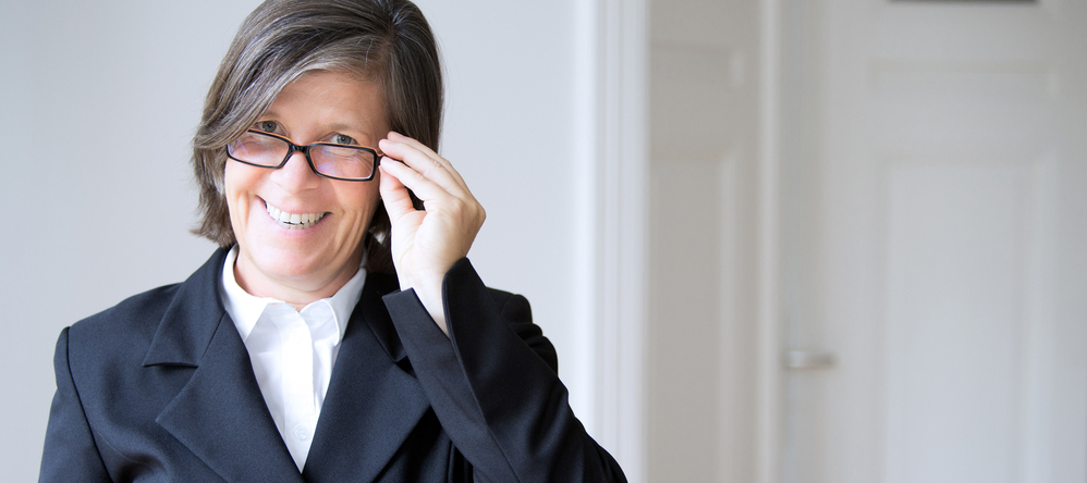Older woman smiling and taking off her glasses
