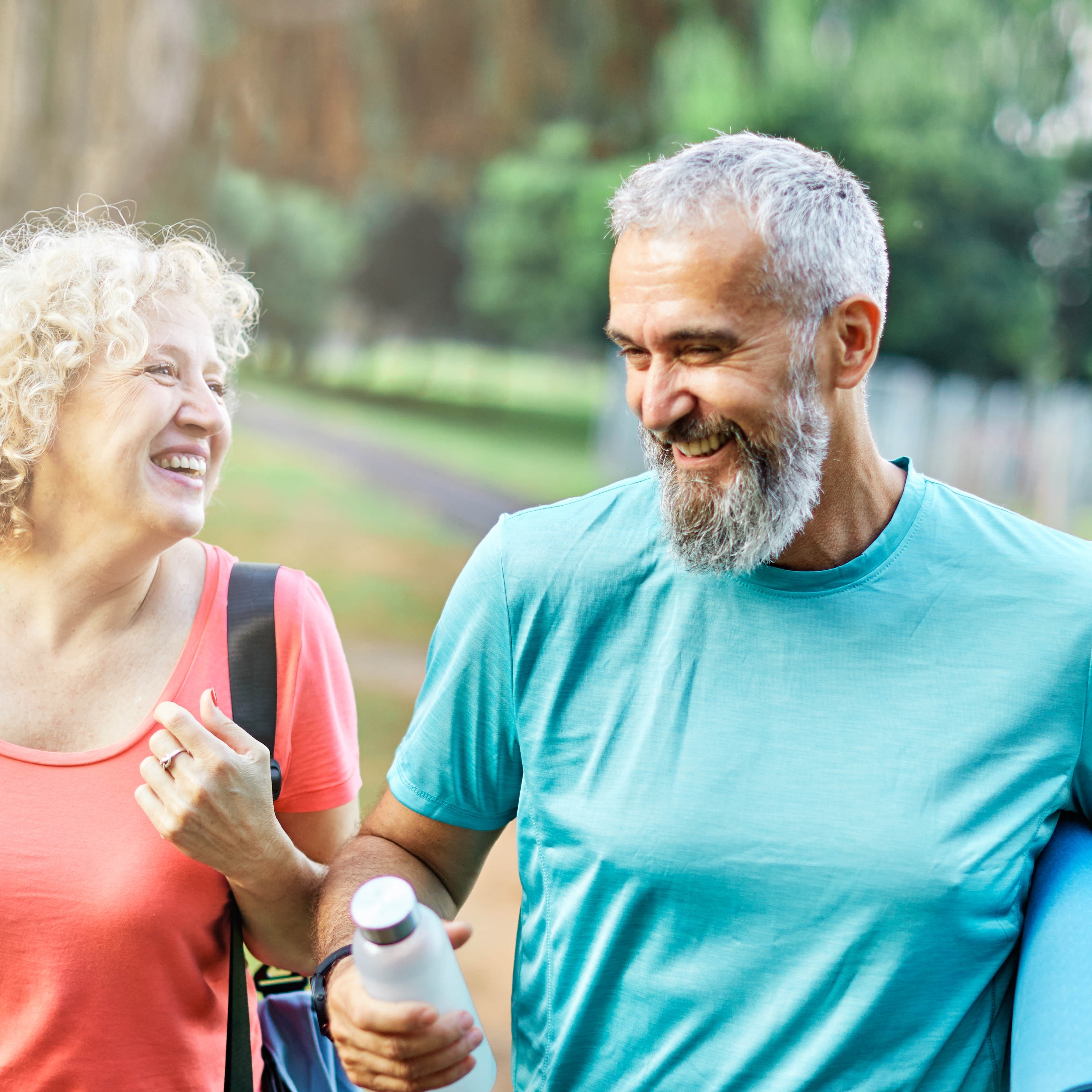 Happy active middle aged couple having fun talking and bonding after having a yoga pilates exercise in park outdoors