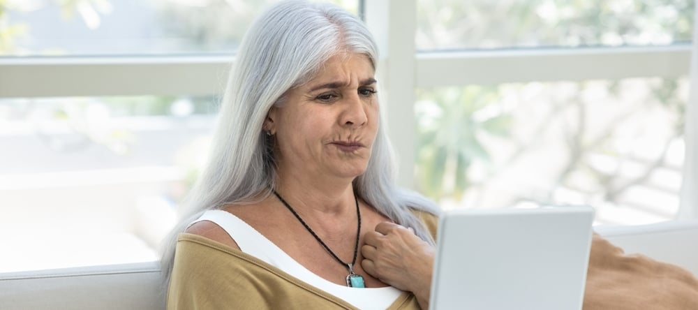 Concerned mature retired Latin woman using tablet at home