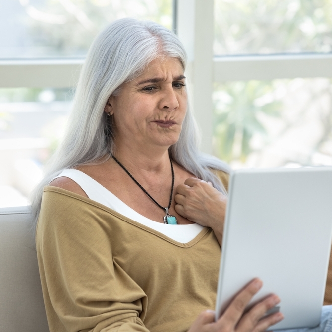 Concerned mature retired Latin woman using tablet at home
