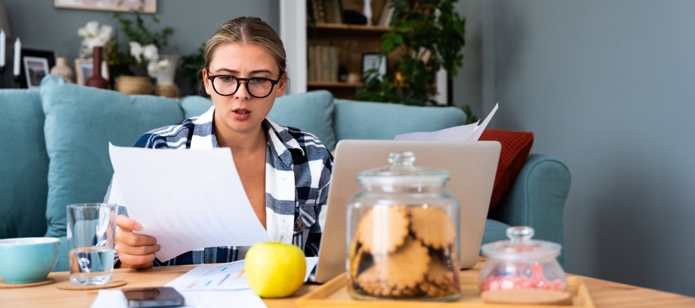 Young woman examining bills owed with a worried expression.