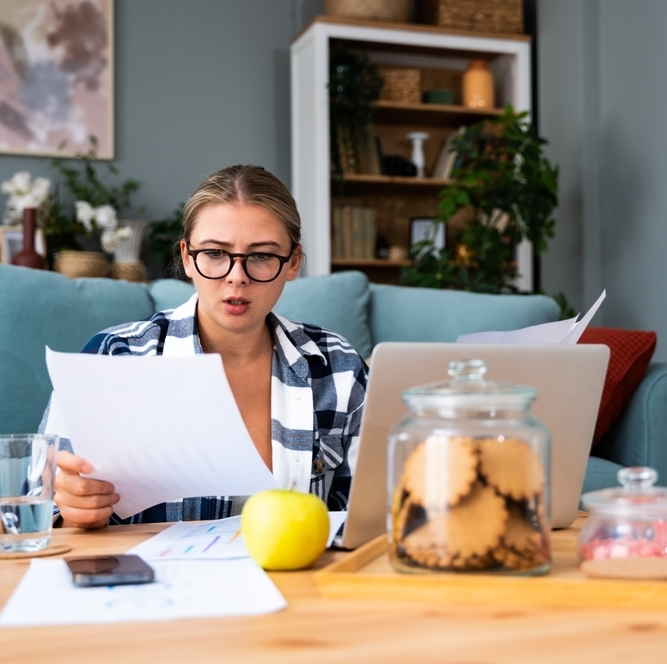 Young woman examining bills owed with a worried expression.