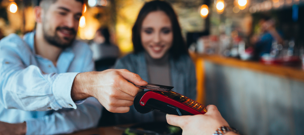 Couple eating out; man paying with credit card at a restaurant