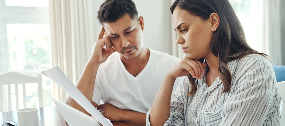 East Indian couple sit at a computer having a stressful conversation