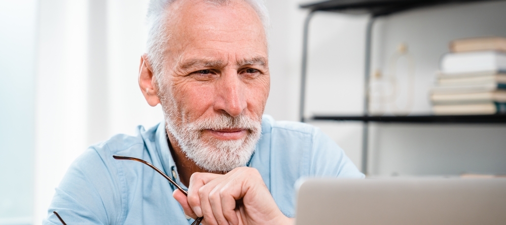 Older man looks at his computer with concern.