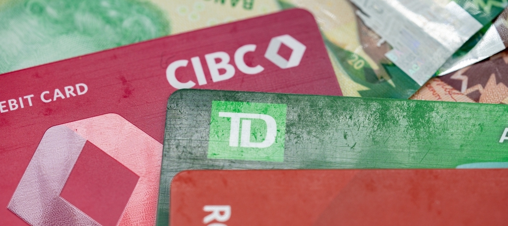 Close up of Canadian bank debit and credit cards with banknotes.