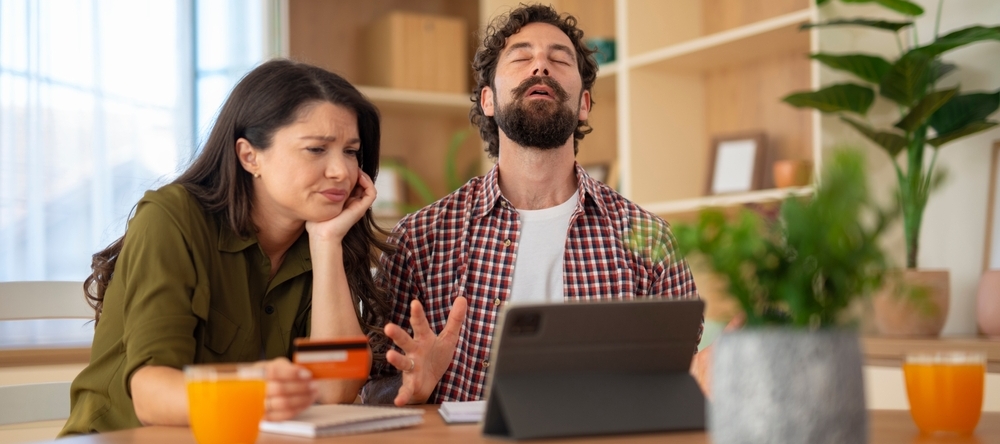 Unhappy couple visibly frustrated with finances.  The woman looks concerned, while the man reacts with stress.