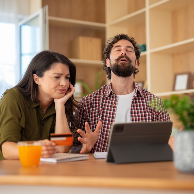 Unhappy couple visibly frustrated with finances.  The woman looks concerned, while the man reacts with stress.