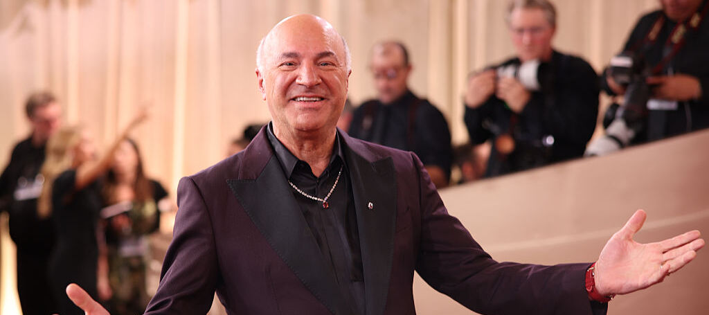 Kevin O'Leary wearing a black suit looking happy