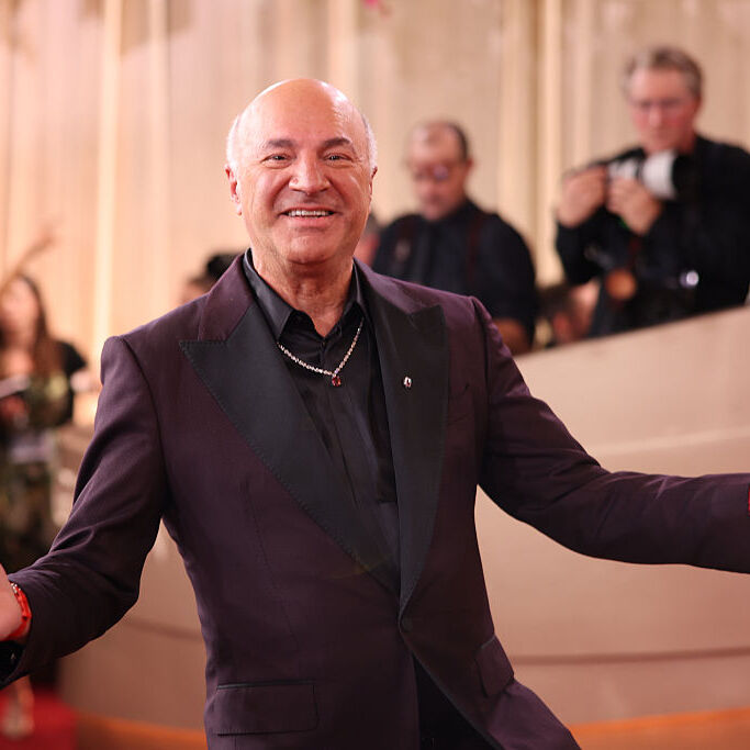 Kevin O'Leary wearing a black suit looking happy