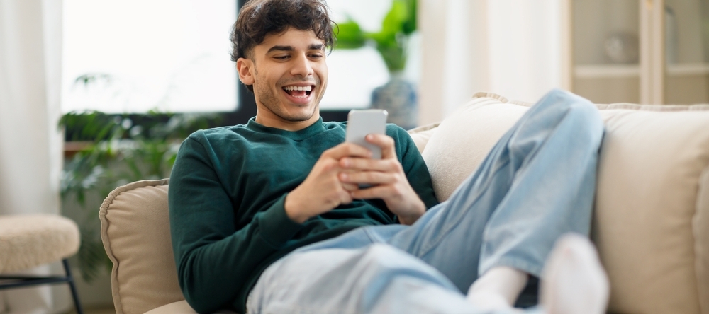 Happy young man on his cellphone trading online