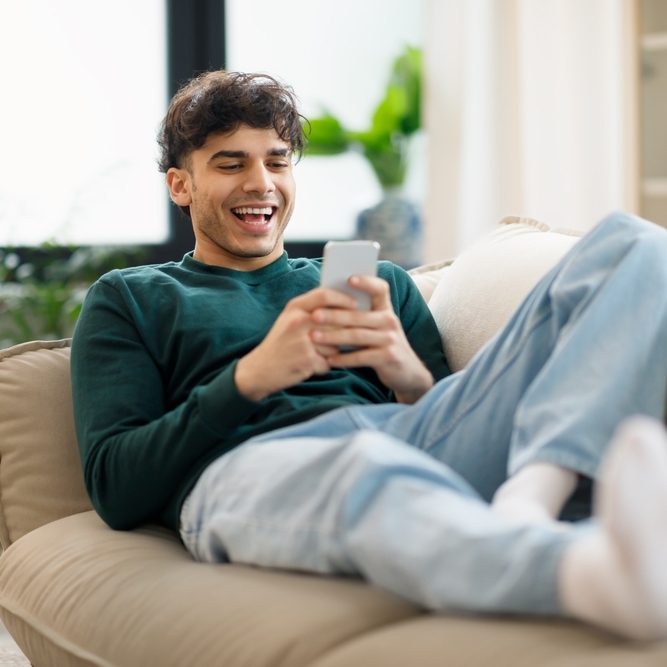 Happy young man on his cellphone trading online