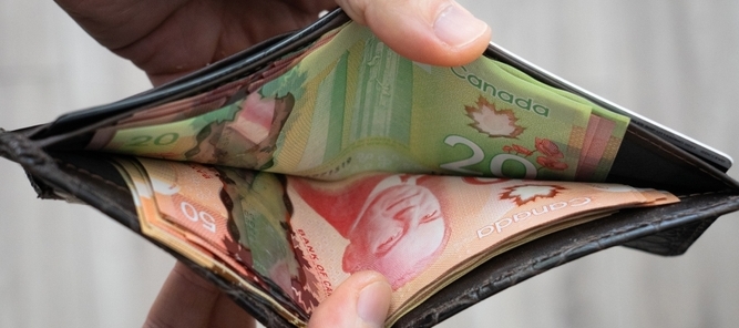 Person opening their wallet looking at Canadian bills