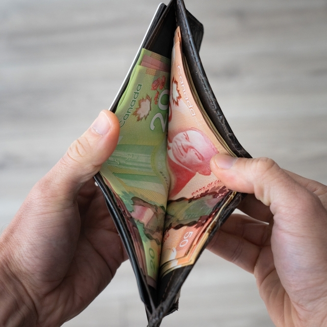 Person opening their wallet looking at Canadian bills