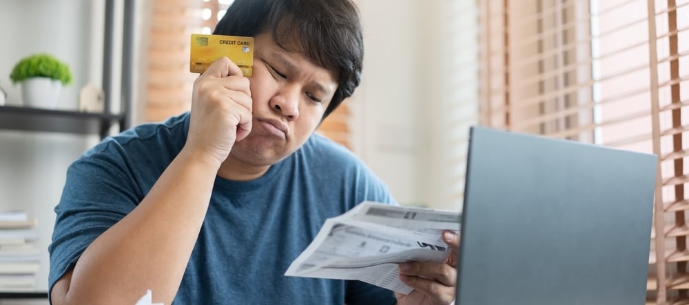 Worried man reviewing credit card bills.