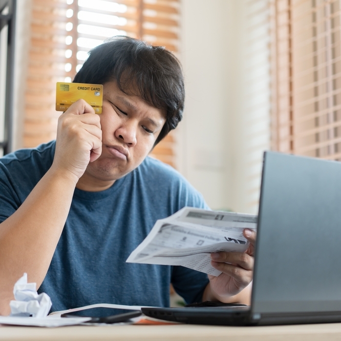 Worried man reviewing credit card bills.