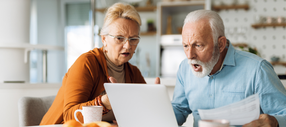Older couple using laptop looking mad