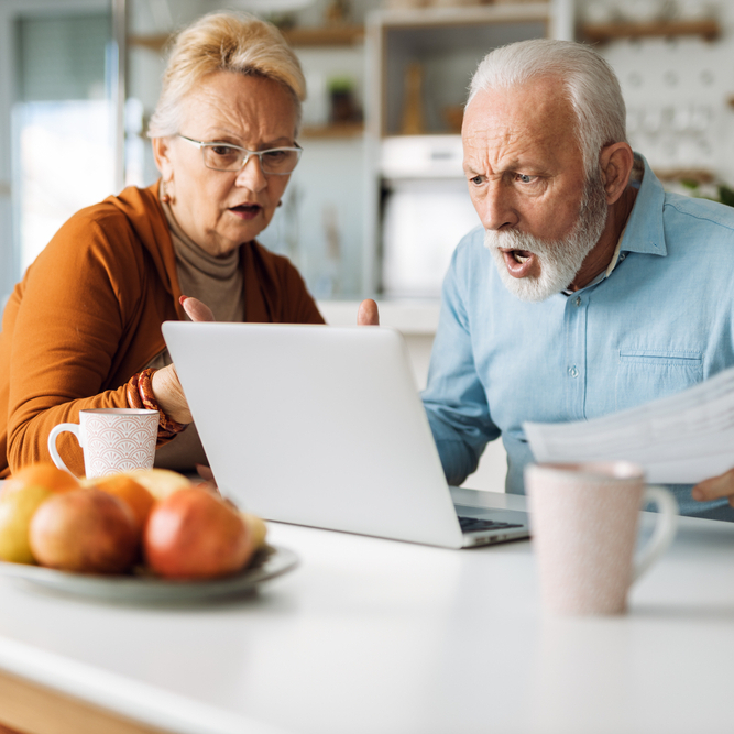 Older couple using laptop looking mad