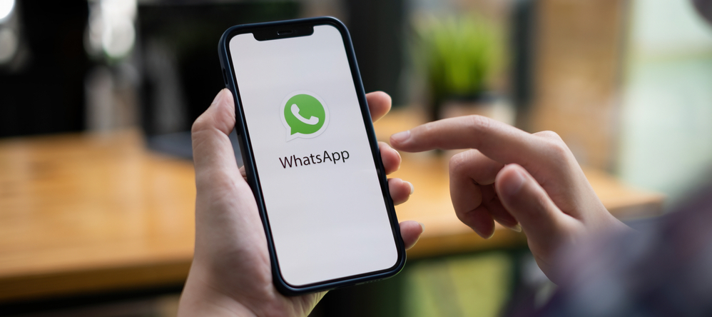 Person holding a smartphone with the Whatsapp logo on it