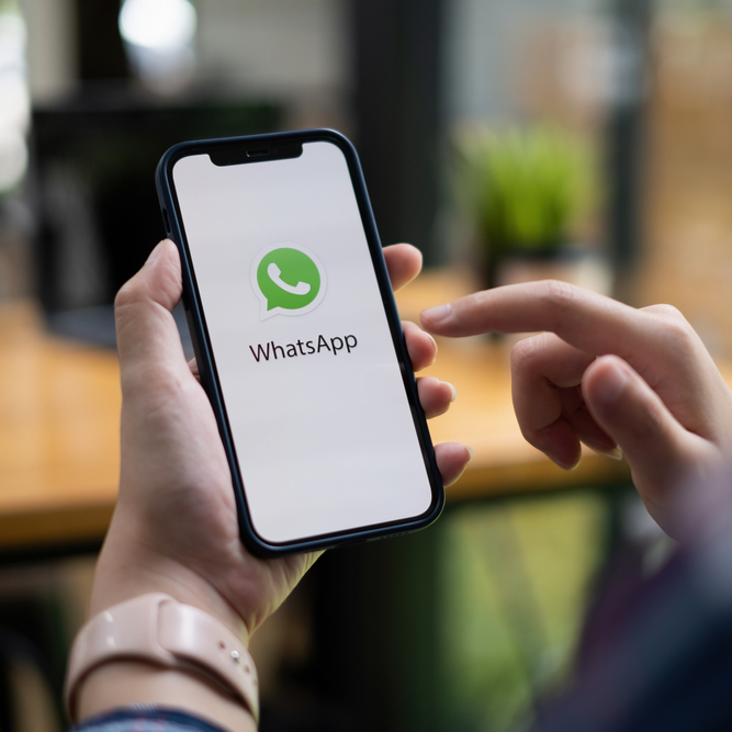 Person holding a smartphone with the Whatsapp logo on it