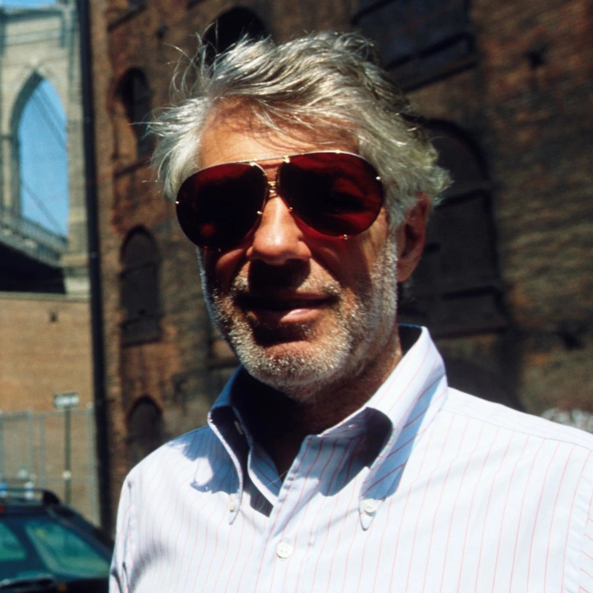 Man wearing sunglasses standing in front of a bridge