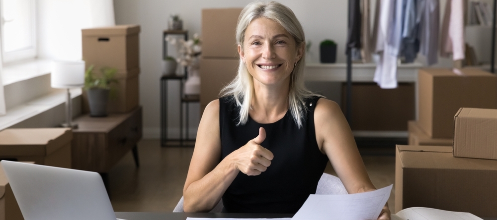 Woman sitting at desk smiling giving a thumbs up