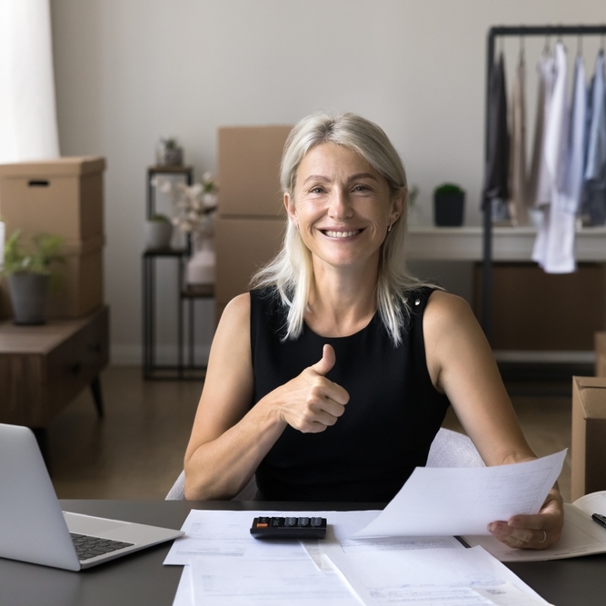 Woman sitting at desk smiling giving a thumbs up