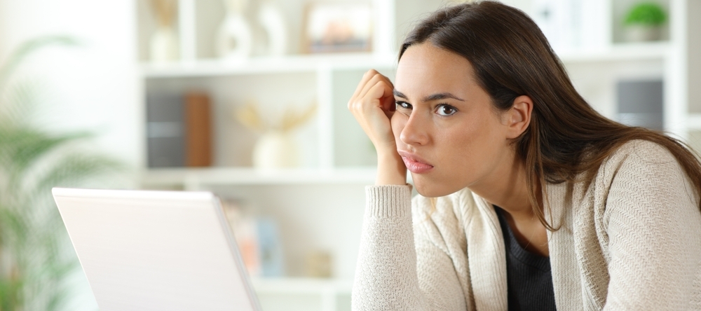 Woman sitting at desk with laptop looking confused
