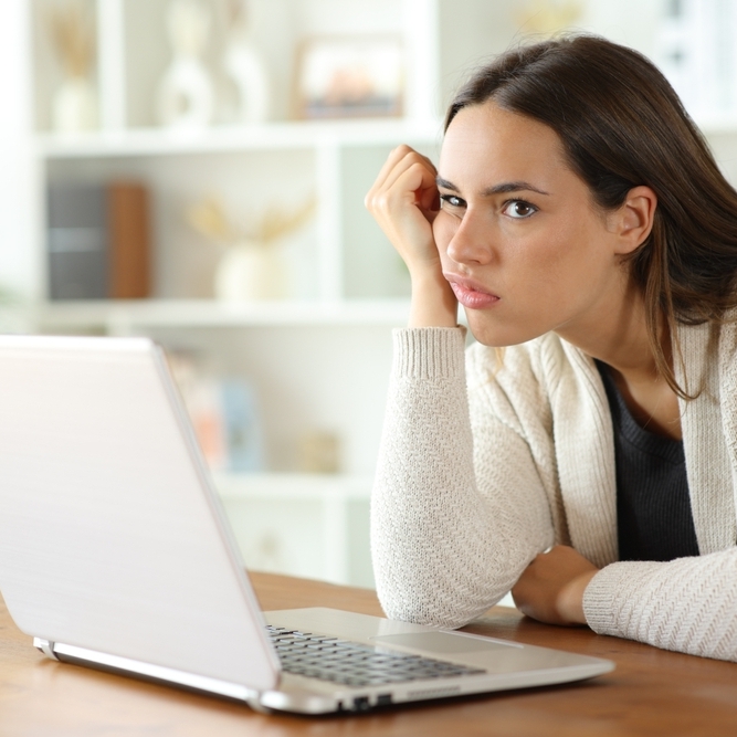 Woman sitting at desk with laptop looking confused