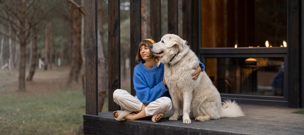 Young woman sitting on cottage porch with dog