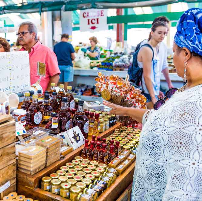 People walking by Maple Syrup products display store stand at Jean-Talon farmers market in Montreal, Quebec