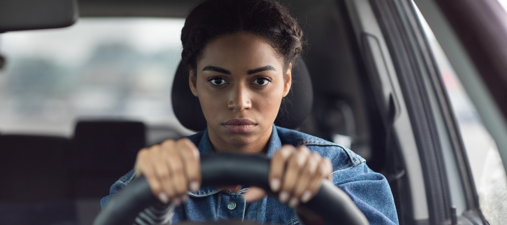 Woman behind the wheel of a car looking stressed