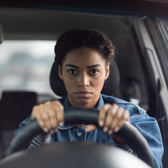 Woman behind the wheel of a car looking stressed