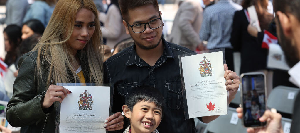 Woman, man and child holding Canadian immigration papers at event welcoming newcomers to Canada