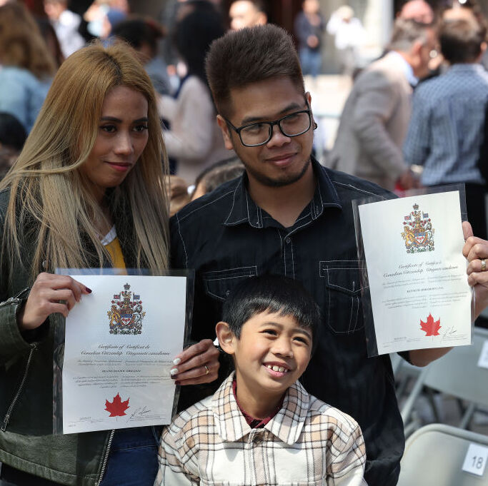 Woman, man and child holding Canadian immigration papers at event welcoming newcomers to Canada