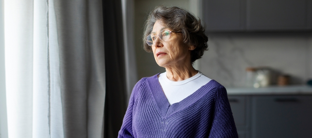 Woman with a sad face looking out a window