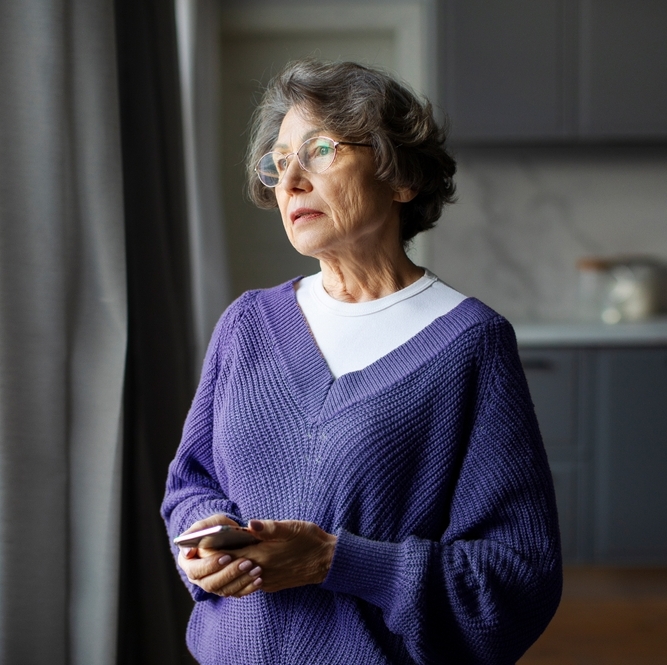 Woman with a sad face looking out a window