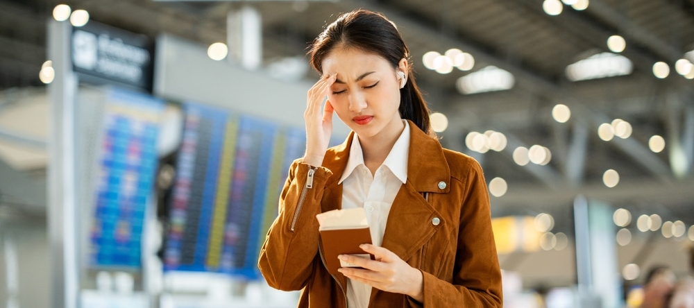 Woman holding passport in an airport looking stressed