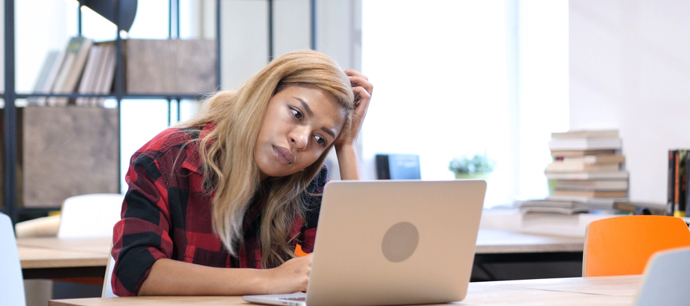 Pensive woman sitting at a laptop.
