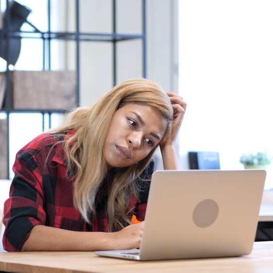 Pensive woman sitting at a laptop.