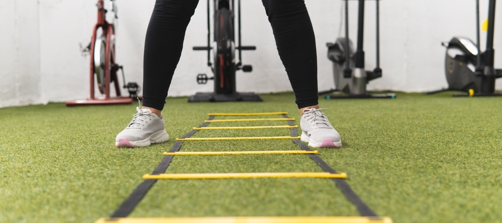 A woman is standing in front of a yellow ladder.