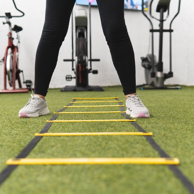 A woman is standing in front of a yellow ladder.